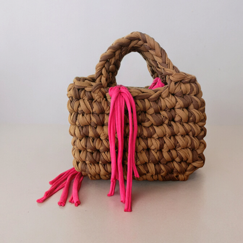 Brown crochet handbag with pink tassels on a light grey background