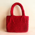 Red crocheted handbag on a beige background