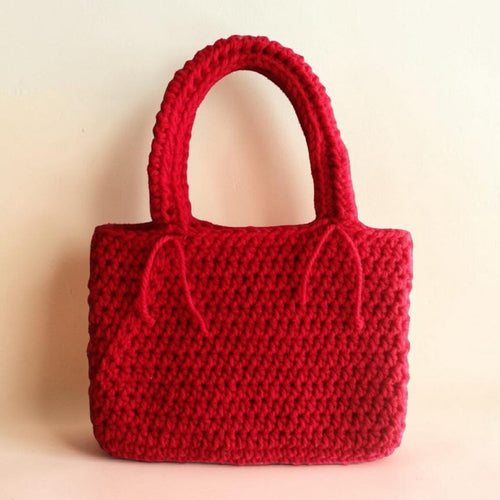 Red crocheted handbag on a beige background