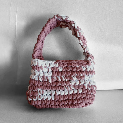 Pink and white crochet handbag on a light grey background